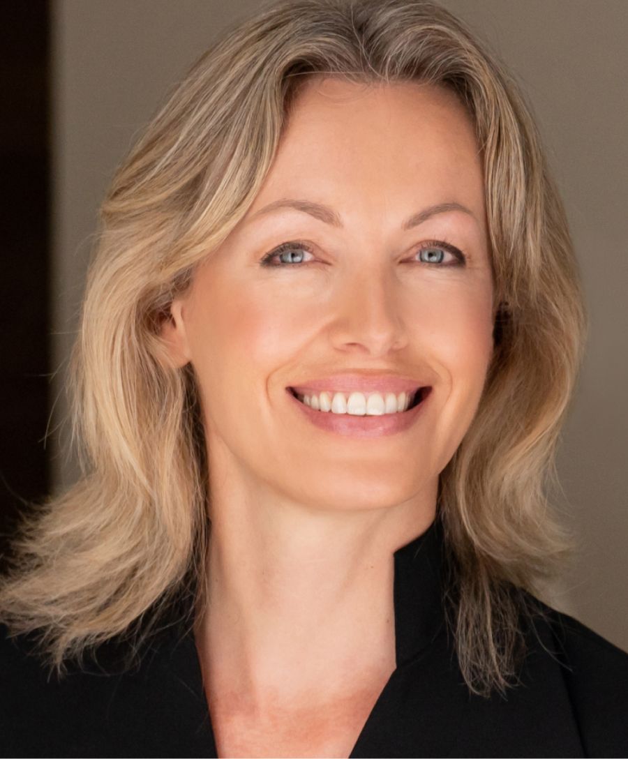 Smiling woman with blonde hair and blue eyes.