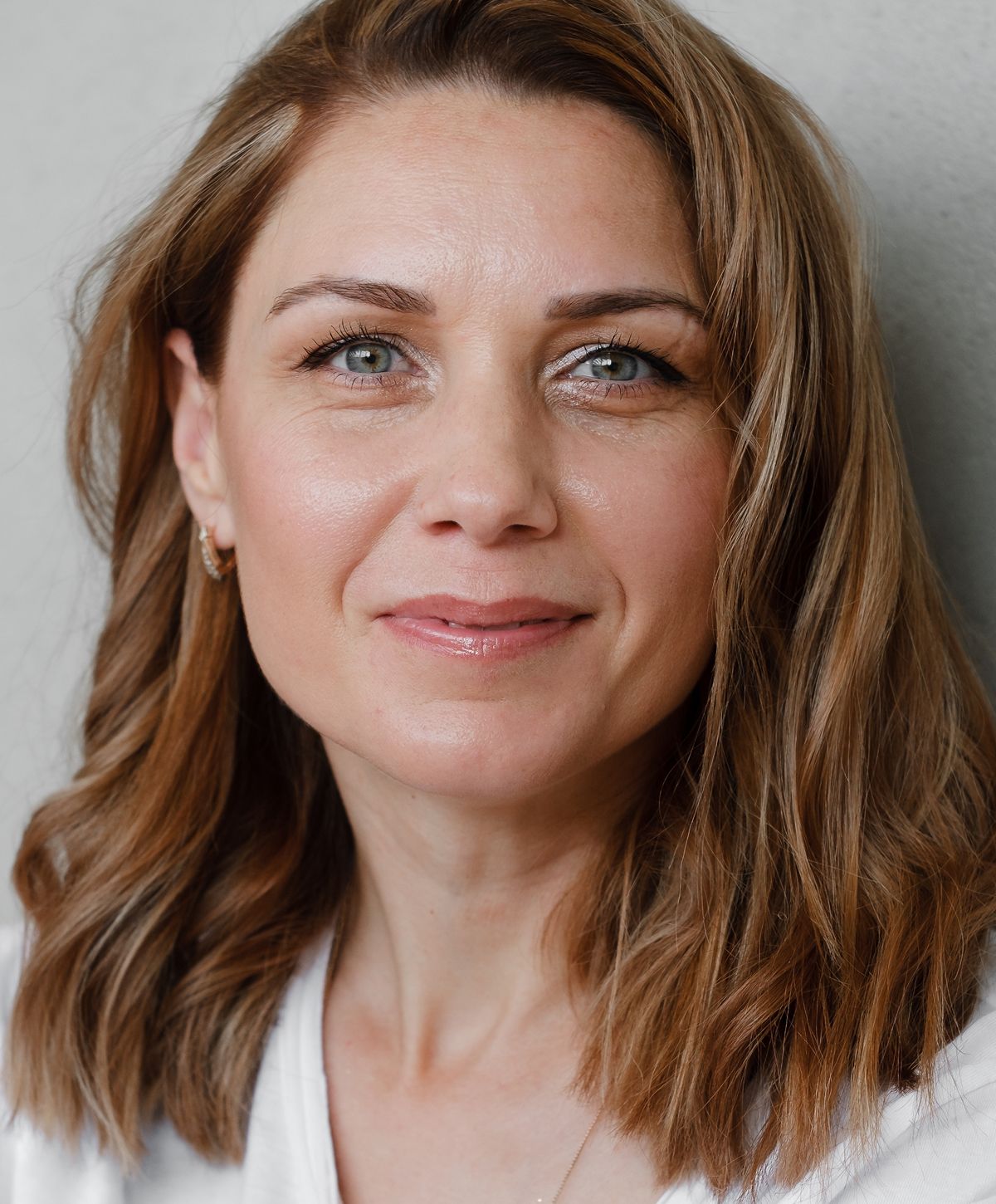 Woman smiling with light makeup and natural hair.
