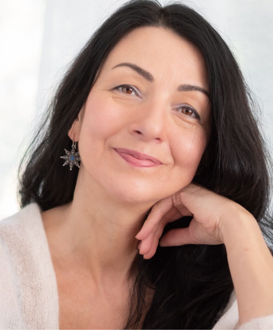 Smiling woman with long dark hair and earrings.