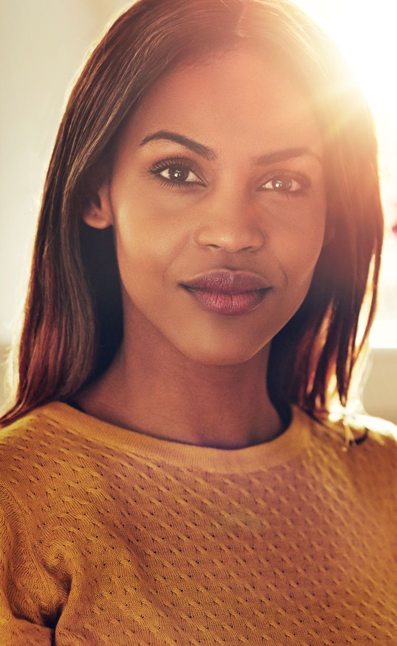 Smiling woman in a yellow sweater, warm lighting.