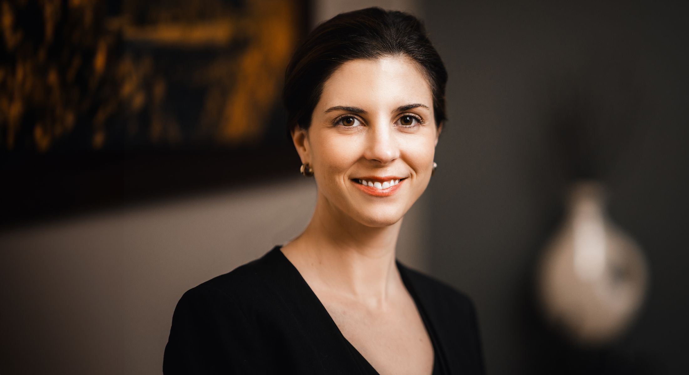 Smiling woman in professional attire, indoor setting.