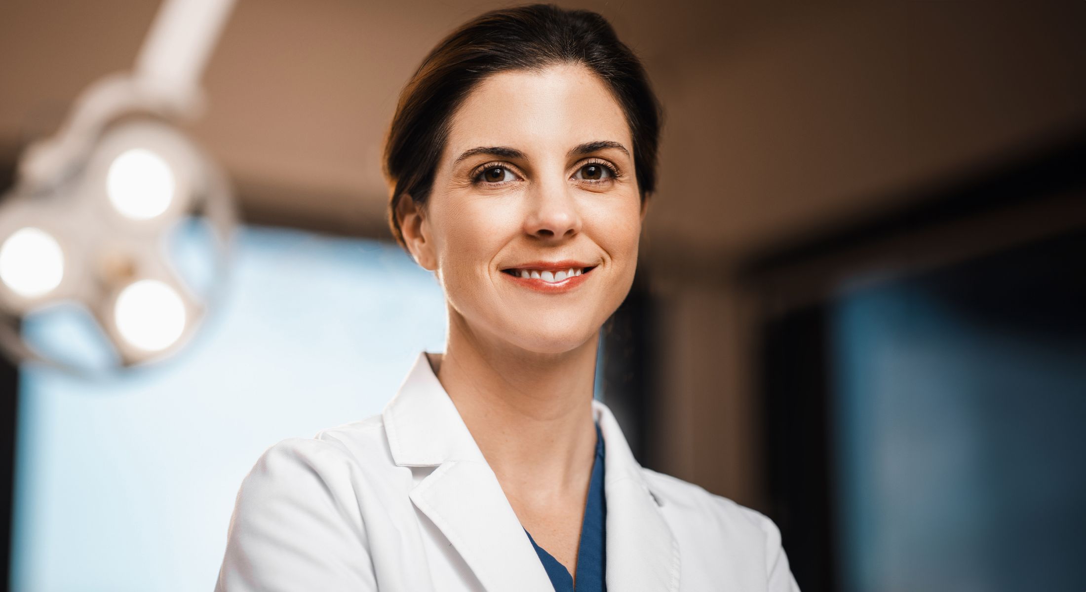 Smiling doctor in medical attire, professional setting.
