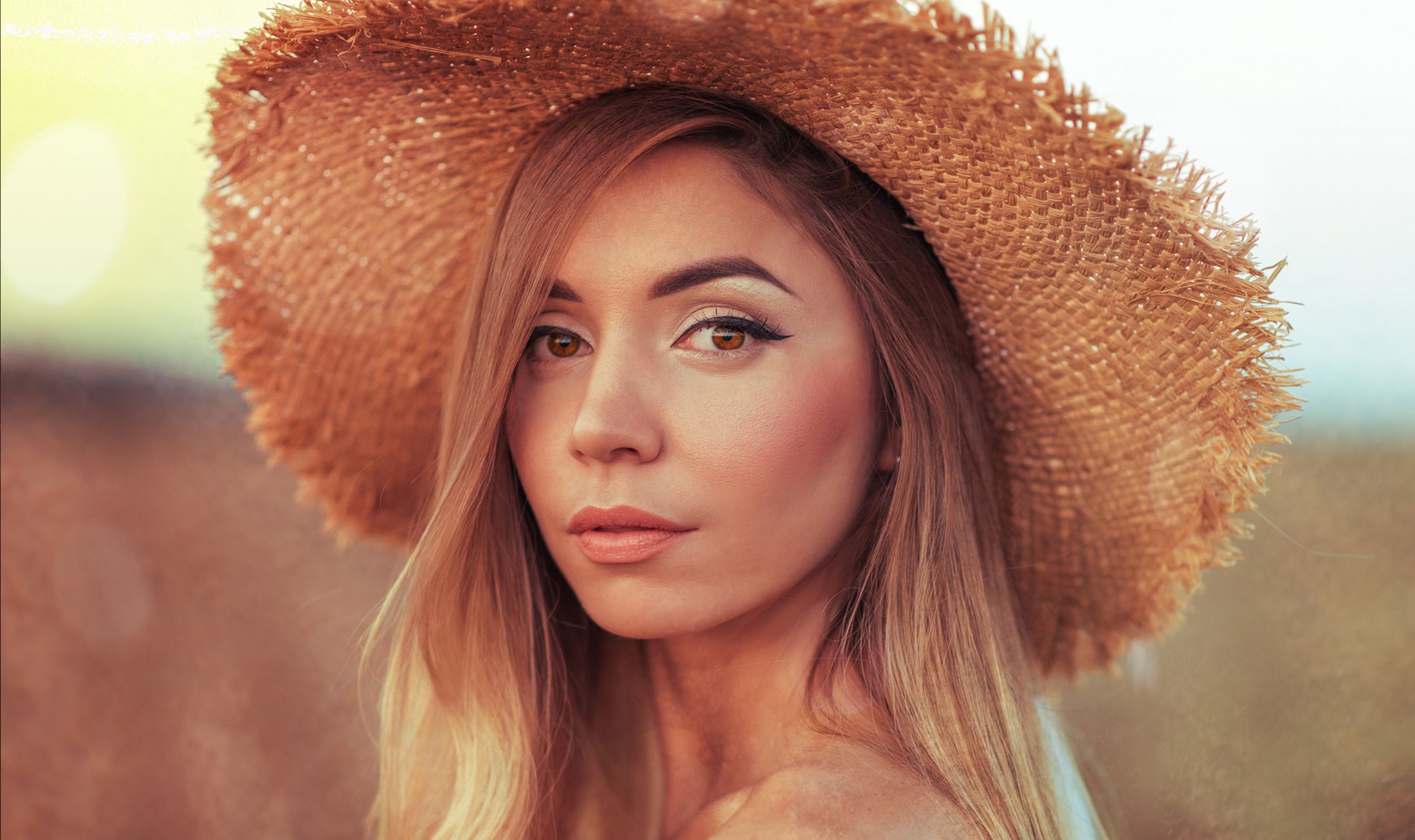 Woman in straw hat with natural makeup.