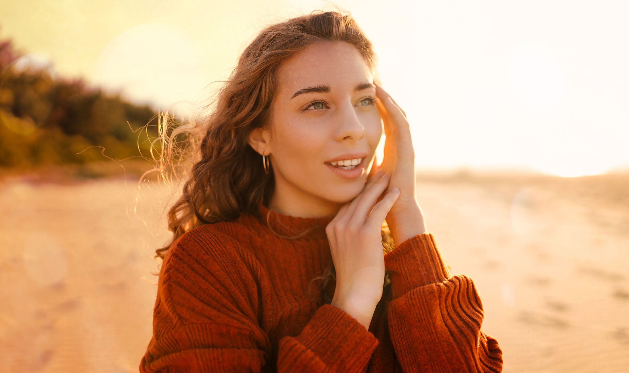 Woman smiling at sunset on a beach.