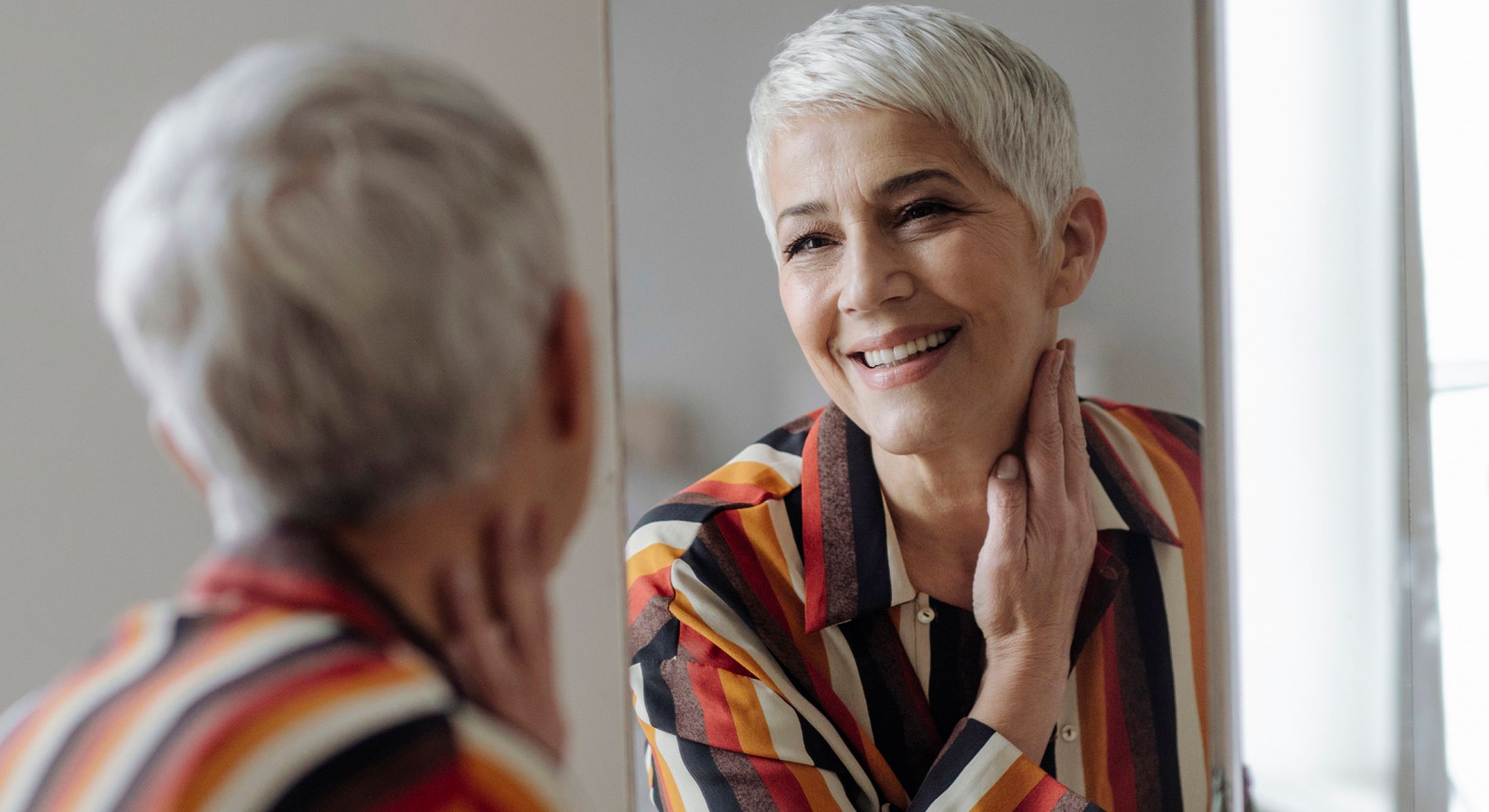 Smiling woman looking in mirror, stylish attire.
