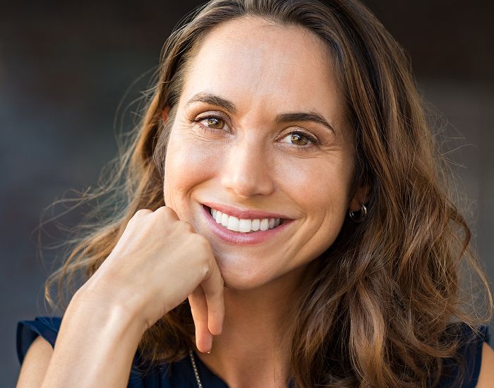 Smiling woman with long, wavy brown hair.