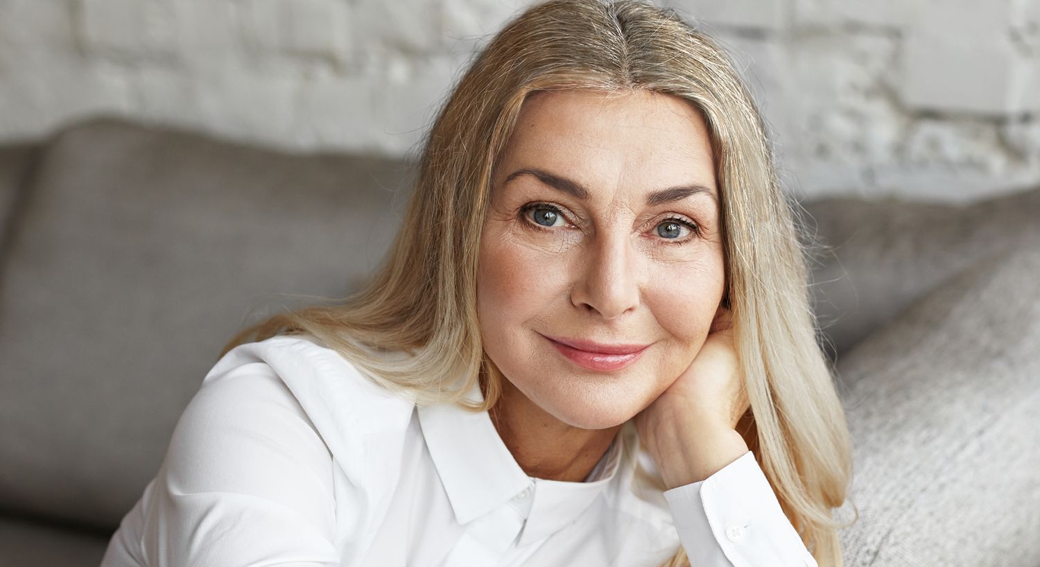 Smiling woman with long blonde hair, relaxed pose.