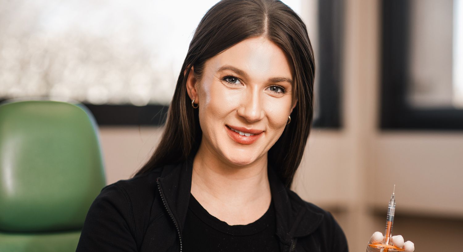 Smiling professional holding a syringe in clinic.